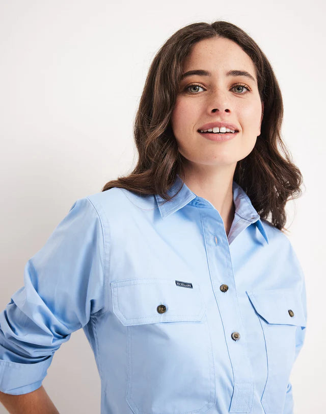 Woman wearing a half button RB Sellars light blue shirt with a plain background