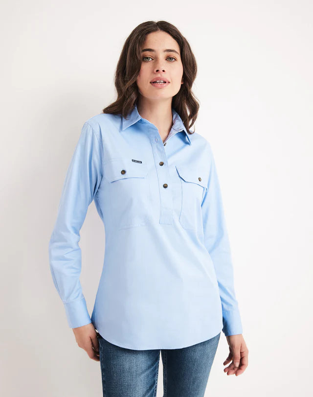 Woman wearing a half button RB Sellars light blue shirt with black buttons on a plain background