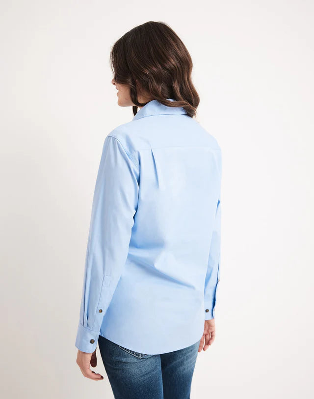 Woman wearing an RB Sellars light blue shirt and jeans on a white background
