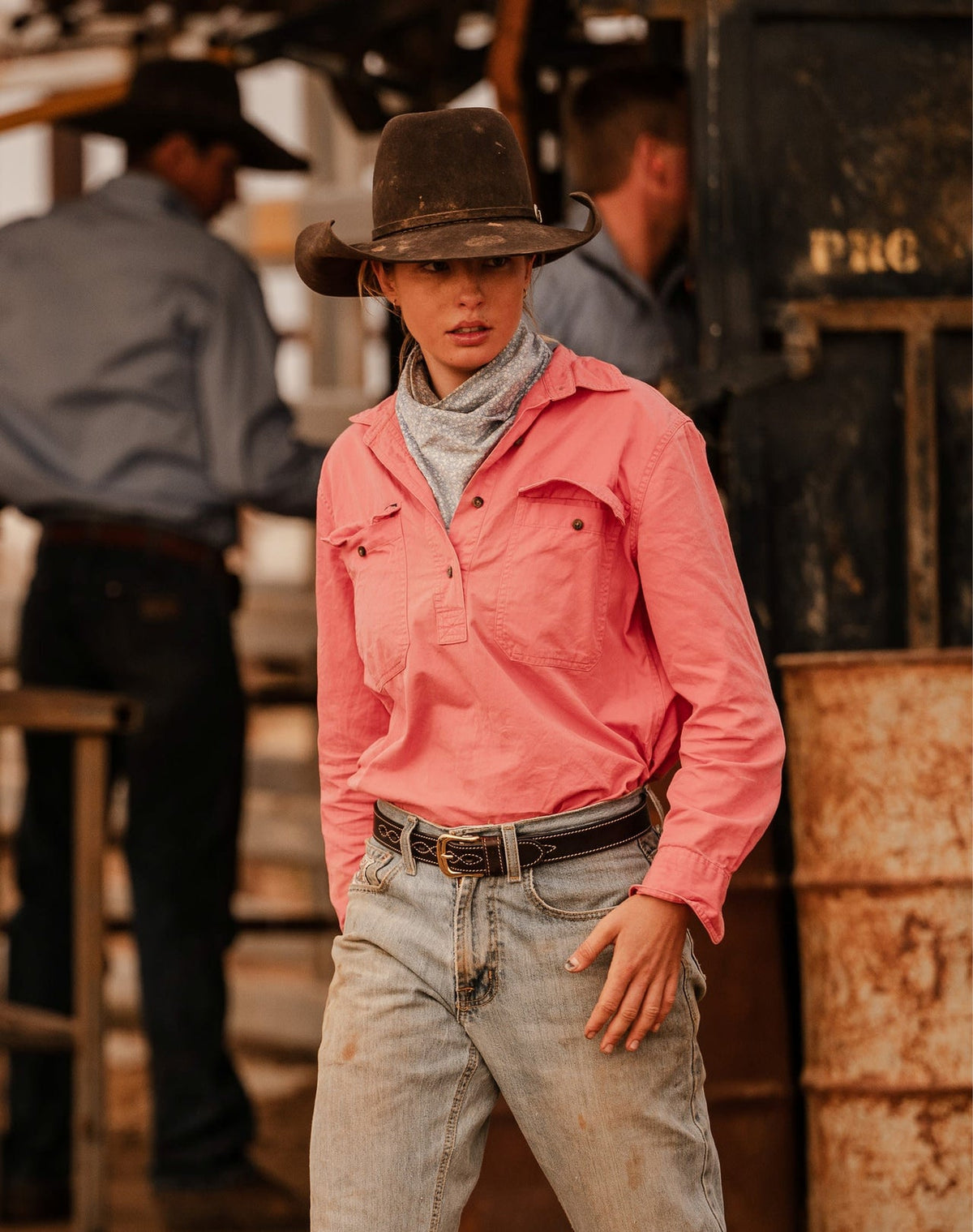 Person wearing a coral Bleak Ridge Clothing RB Sellars shirt and cowboy hat in a rustic setting