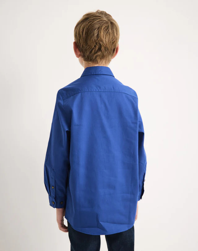 Boy wearing a royal blue RB Sellars shirt from behind on a white background